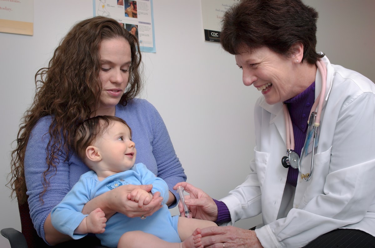 A smiling pediatrician caring for an infant held by a parent