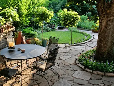 Flagstone patio with wrought-iron furniture set in a shaded garden courtyard