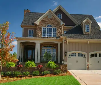 Stone-and-siding home framed by clean foundation plantings and a green lawn