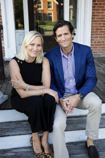 Dalia and Mark Metzger sitting together on steps outside their home