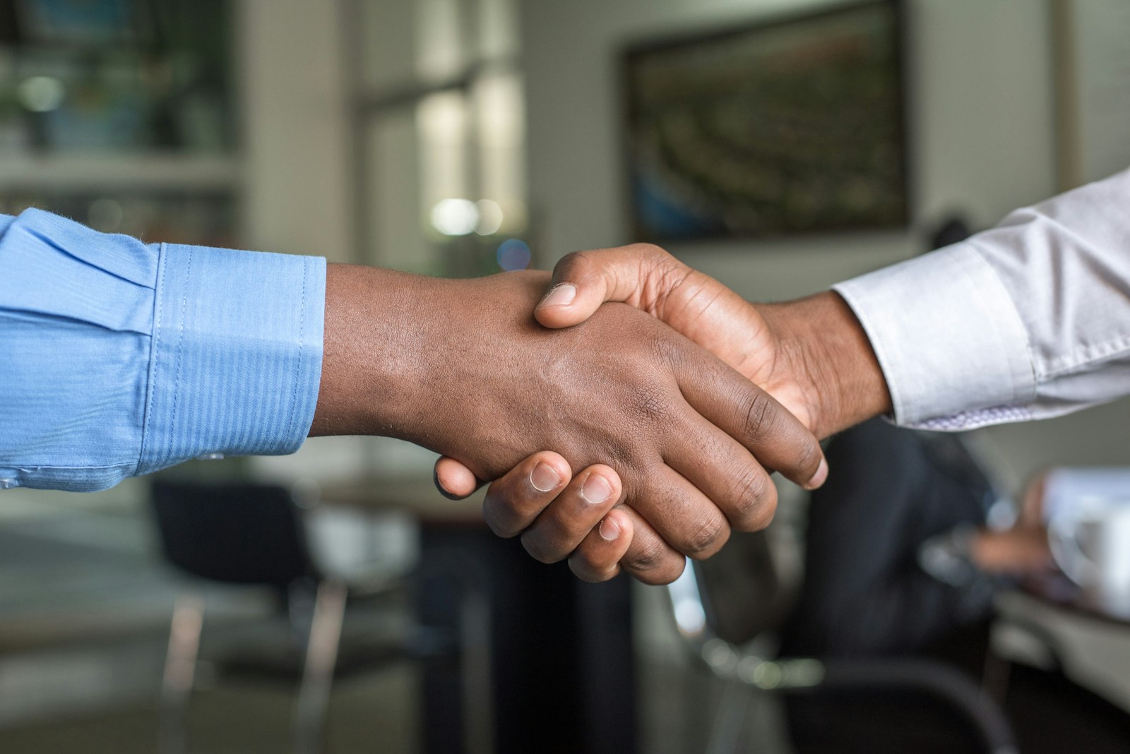 Two pairs of hands negotiating across a wooden conference table with documents.