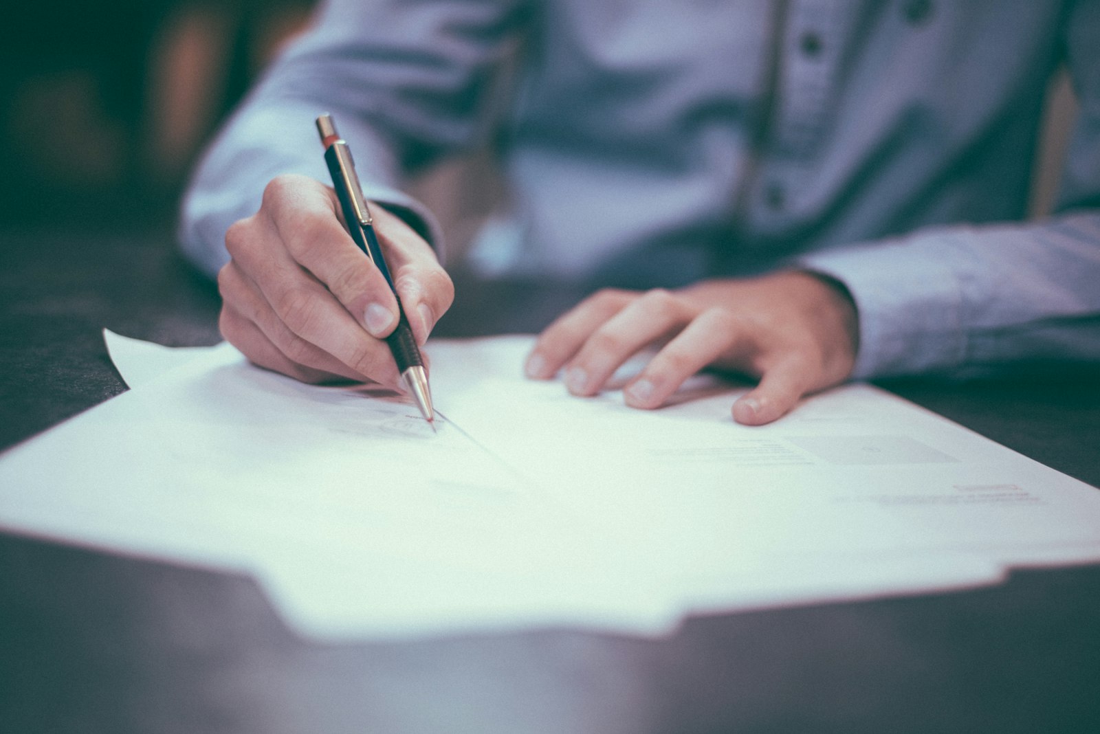 A calculator, financial documents, and a wedding ring on a wooden table.